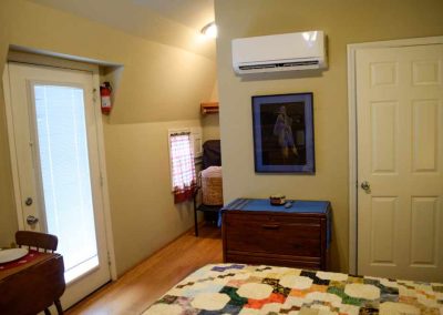 Cozy bedroom with modern air conditioner and quilted bed