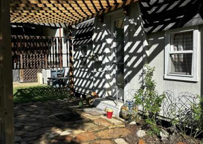 Sunny garden path with wooden pergola and shaded walls