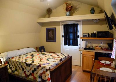 Cozy attic studio apartment with kitchenette and quilted bed
