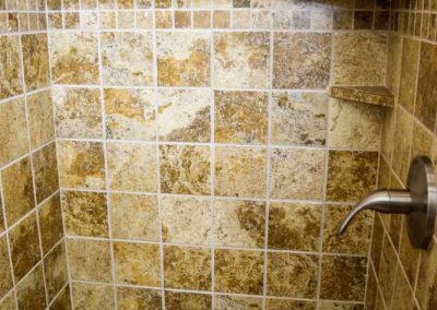 Tiled shower interior with hygiene products on shelf