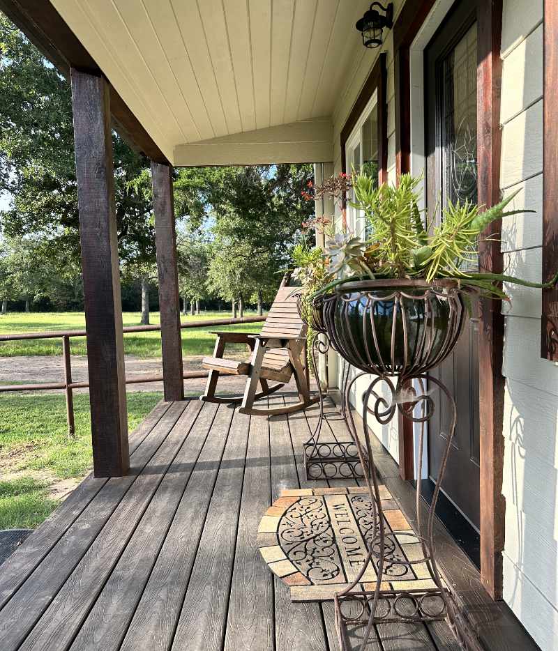 Cozy wooden porch with chairs and hanging plants