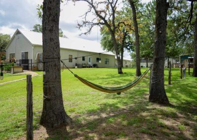 Hammock between trees in sunny backyard with houses