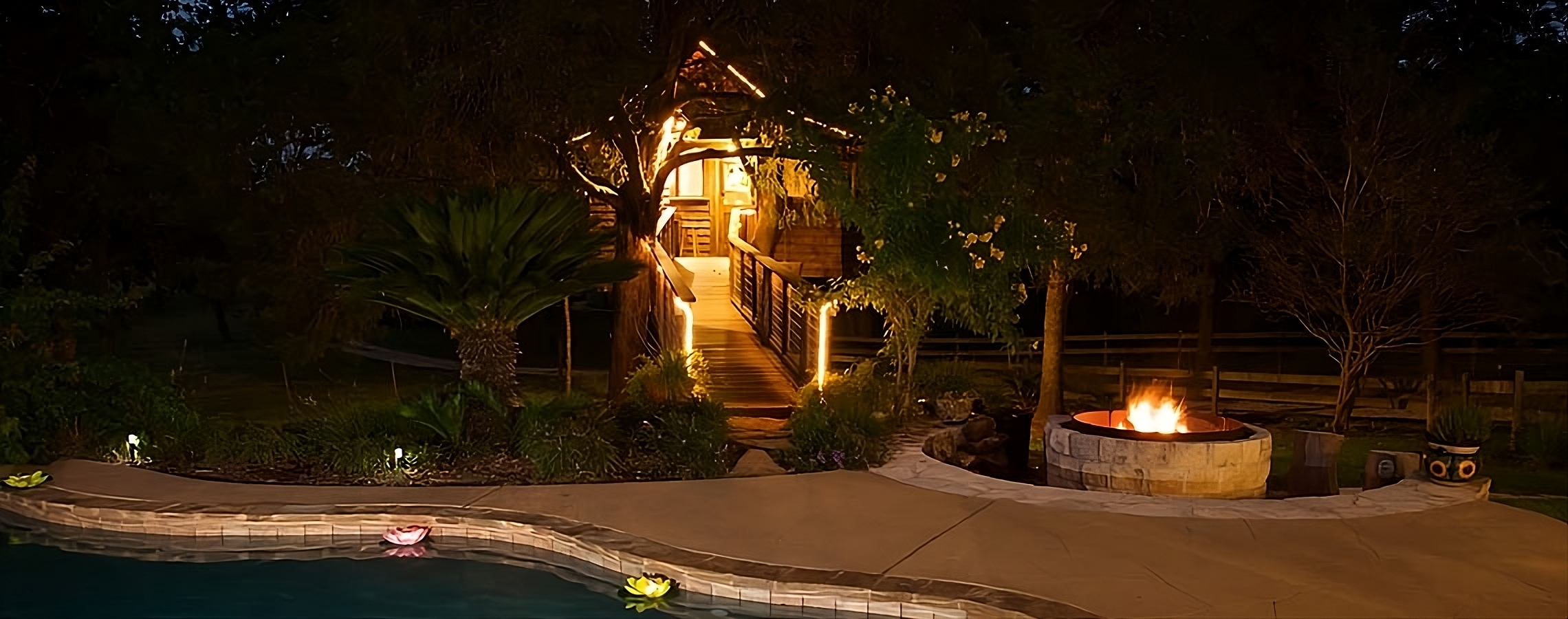 Illuminated treehouse by poolside at night