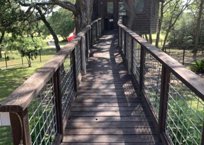 Wooden bridge leading to rustic treehouse surrounded by trees